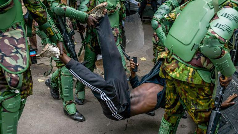  Kenyan police officers intervene in people during a protest against the tax hikes in planned Finance Bill 2024 as they march to the parliament building in Nairobi, Kenya on June 27, 2024