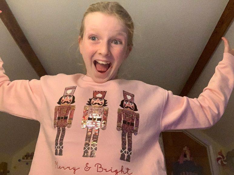 A girl in a Christmas jumper showing three kings