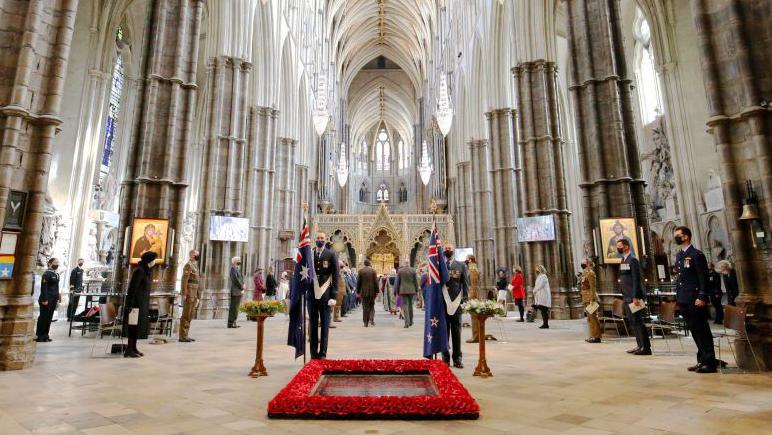 The tomb of the unknown warrior in Westminster Abbey with soldiers and mourners in the hall