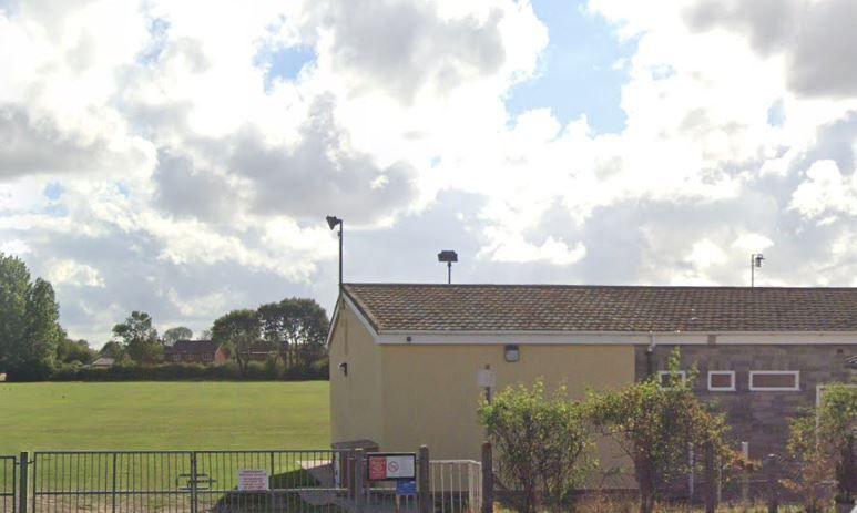 Google view of the playing field and pavilion. The cream-coloured pavilion sits on the perimeter of the field, with trees visible in the distance.