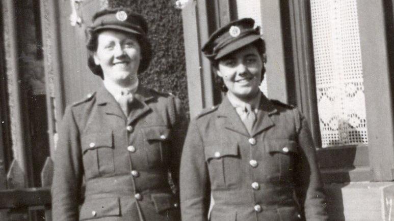 Christina Hartnell is standing outside her home in Hazelrigg, Newcastle with another woman. They are both in uniform.