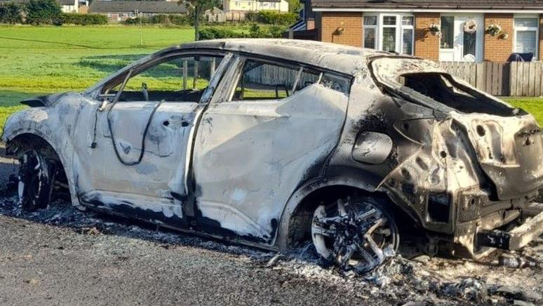 Shows a burnt-out car