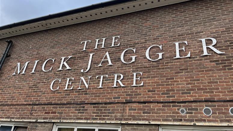 A brick wall adorned with silver letters that read The Mick Jagger Centre.