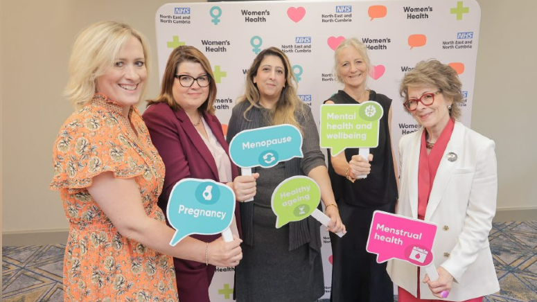 Five women hold placards reading: "pregnancy", "menopause", "mental health and wellbeing" and "menstrual health"