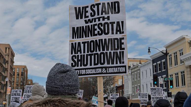 A demonstrator holds an anti-ICE sign that reads "We Stand with Minnesota, Nationwide Shutdown" during a protest in Washington DC