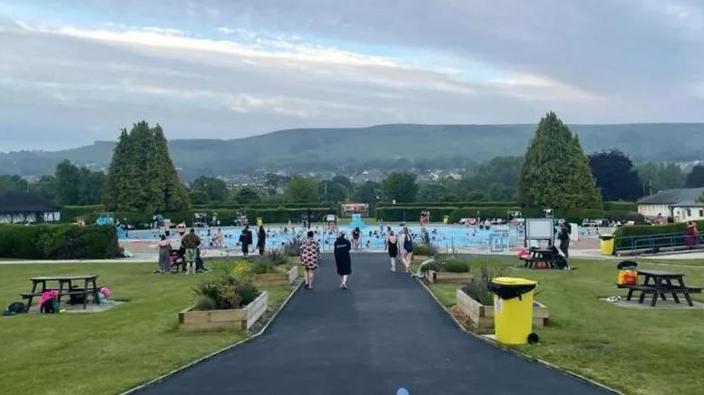 Swimmers at Ilkley lido, view from the Grade II listed cafe with the pool and moors in the background 