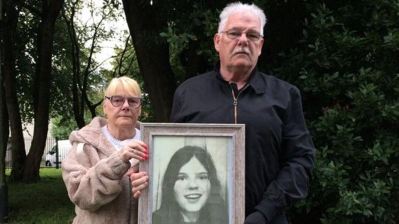 May and Martin McGavigan holding a photo of their teenage sister, Annette  