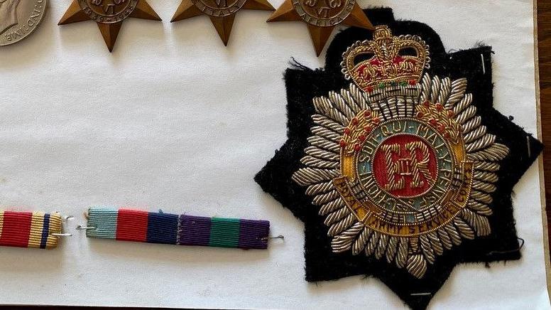 A close up picture of a black medal with the royal crest on it.