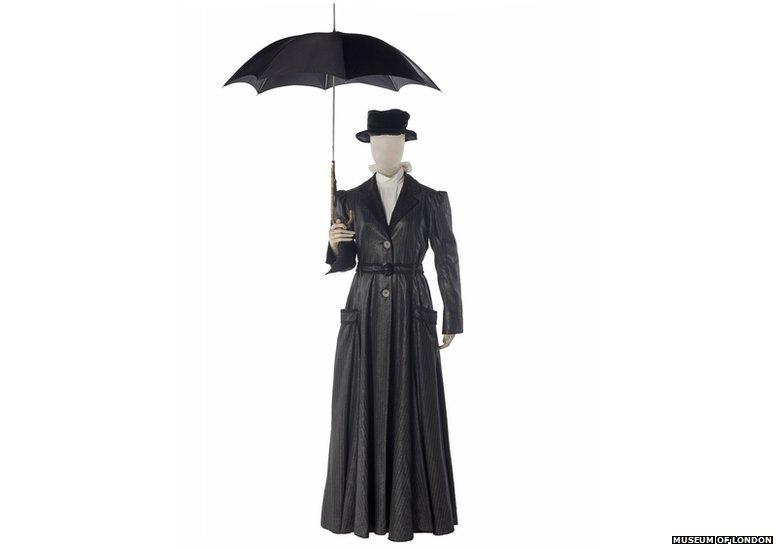 Black costume with a long coat and a black traditional looking umberella