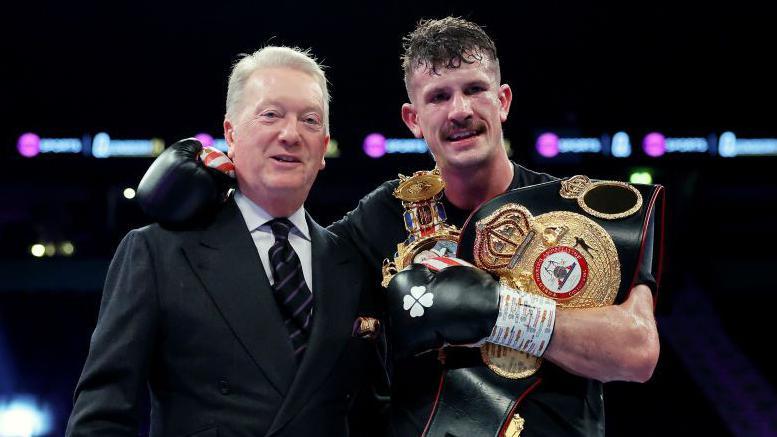 Nathan Heaney stands next to his promoter Frank Warren with the British and WBA Continental middleweight belts over his shoulders.