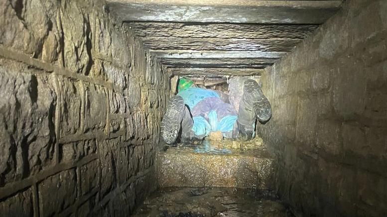 The feet of a contractor in an underground tunnel