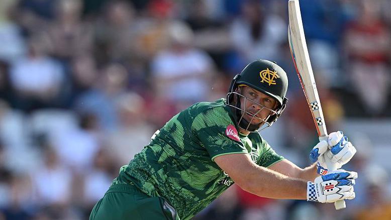 Nottinghamshire's George Munsey, wearing a green shirt and green helmet and white gloves, plays a shot with his bat