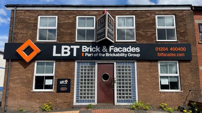 A building with a sign for LBT Brick and Facades