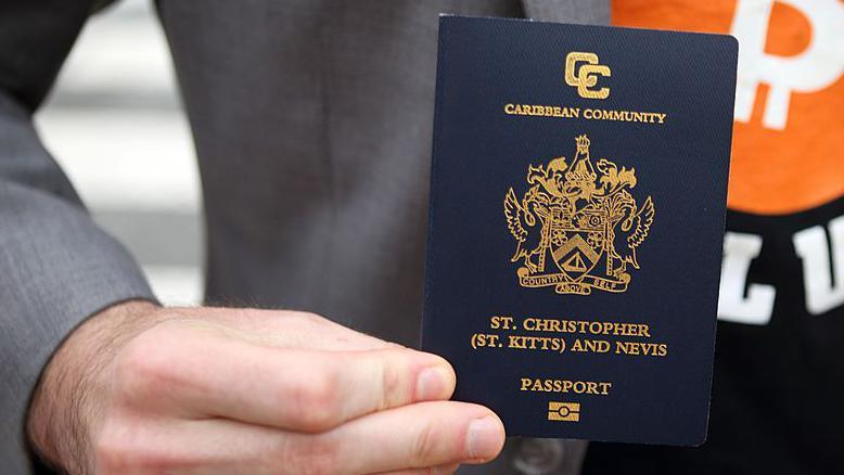 A man holding a St Kitts passport