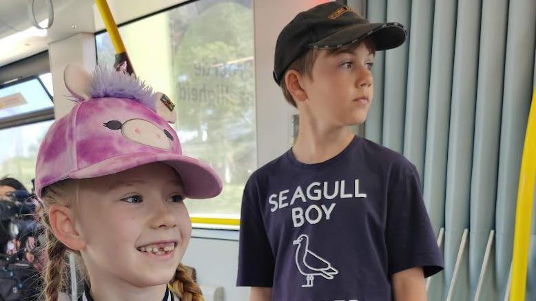 A boy and a girl in caps. The boy's T-shirt says "Seagull Boy"