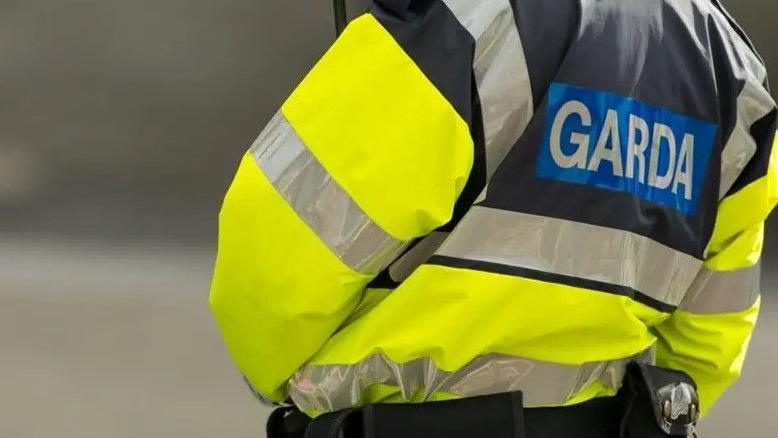 a police person's jacket seen from behind - it reads "Garda" which is Irish for police