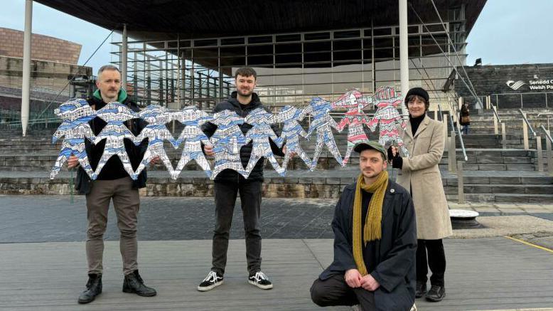 Arddangos cadwyn bapur ar ffurf plant ar risiau'r Senedd