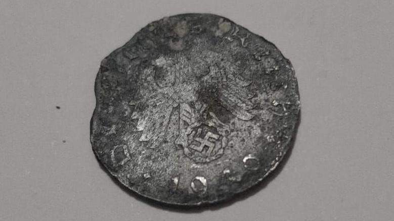 Heavily damaged and worn German coin. The Reichsadler - an heraldic eagle - on top of a swastika can be seen on the Reichsmark and the date 1940 can be seen on the lower edge of the coin as well as letters from Deutsches Reich around the rest of the edge.