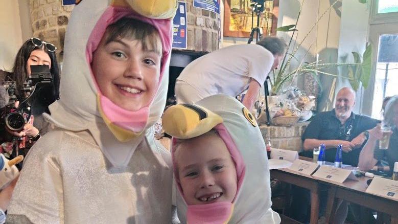 A smiling boy and girl in seagull costumes