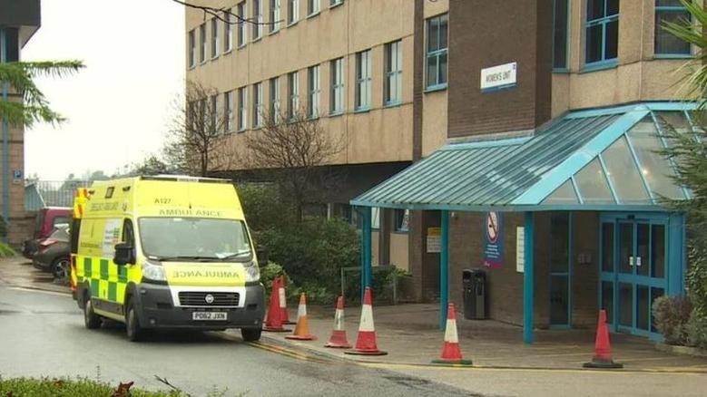 An ambulance parked outside the Royal Lancaster Infirmary building, with orange cones outside the door entrance