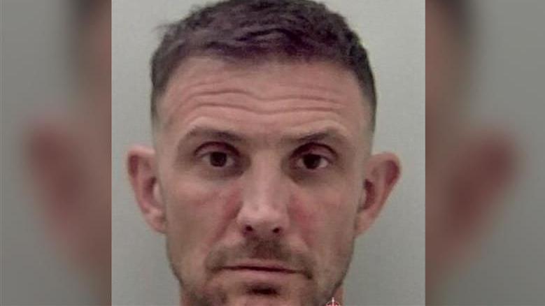 A police mugshot of Wayne Blackburn, 43. He is a white man with brown eyes, short brown hair and slight brown stubble. 