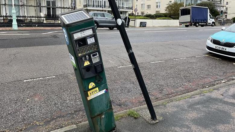 An old parking machine which is no longer in use tilting to one side