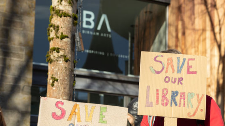 With the Birnam library in the background, a banner reading 'Save Our Library' can be seend.