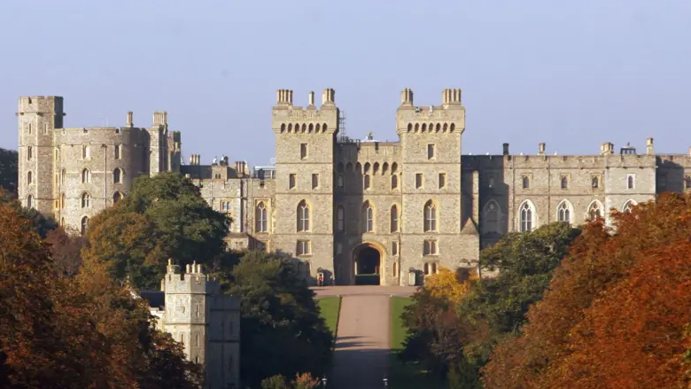 Windsor Castle. The shot is taken from the distance looking towards the castle. A tree-lined drive leads to the castle entrance.