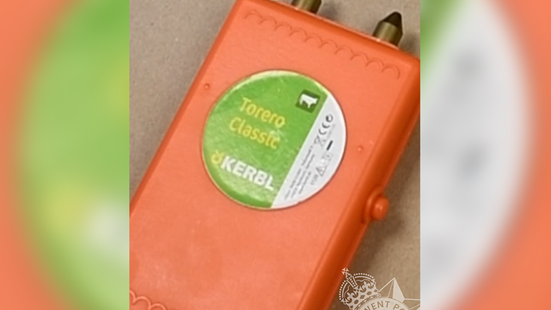 An orange cattle prod with a green and white sticker