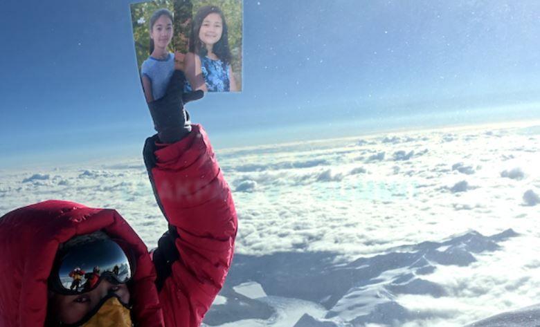 Lhakpa Sherpa raises a photograph of her daughters above the clouds