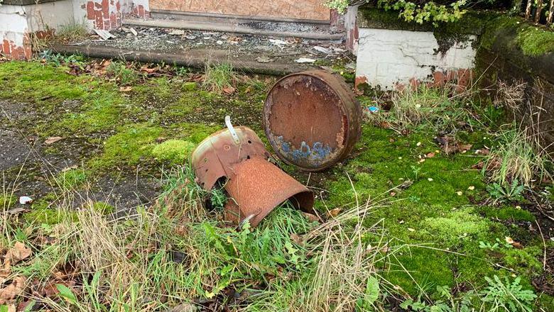 An old oil drum sits on grassy ground and falls into a state of decay