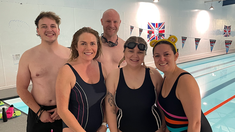 Jordan Blyth, Claudia Robinson, Mark Drury, Eve Kennedy and Rachel Teate all wearing swimming costumes and standing in front of an indoor pool.