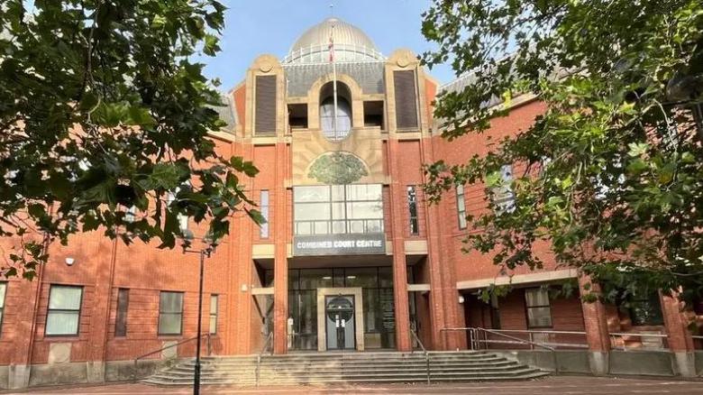 Hull's Combined Court Centre - a large, red brick building, with steps leading up the doors and trees on either side