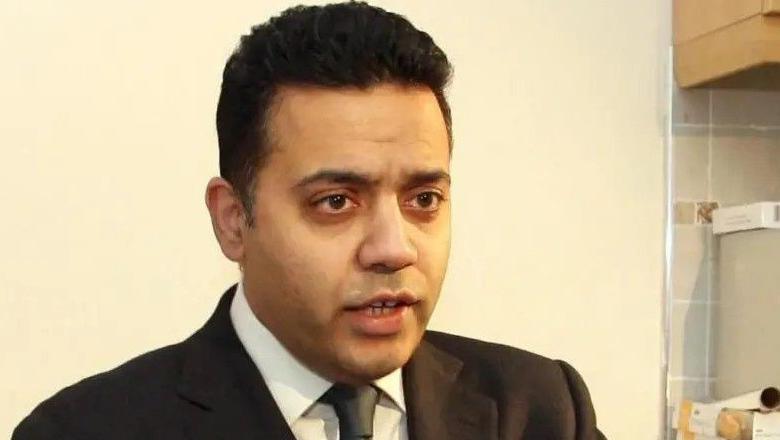 Former Dewsbury MP Shahid Malik: a man wearing a smart dark suit and tie. He is stood in what appears to be a kitchen.