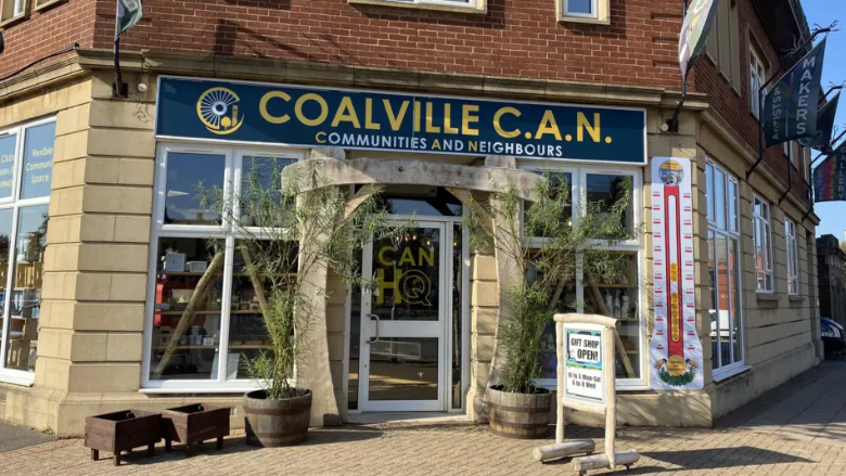 A community centre with a large sign above the door and planters outside