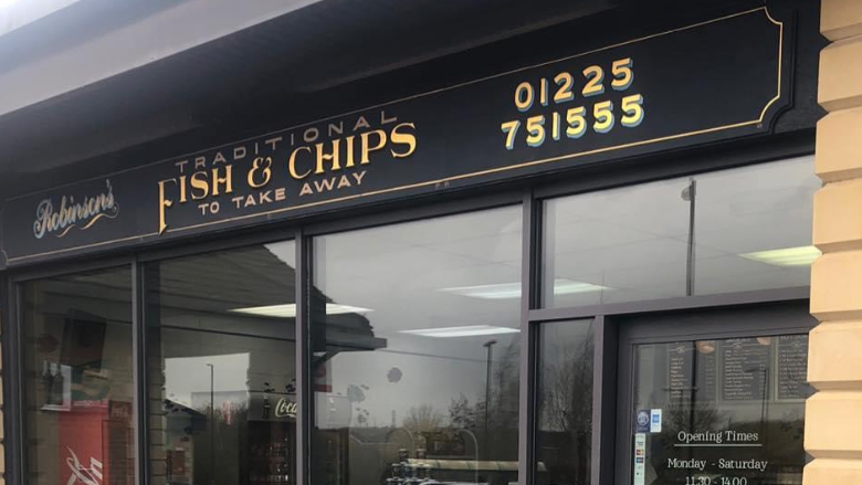 Front of fish and chip shop with sign that reads "Robinson's Traditional Fish and Chips to take away" and their phone number