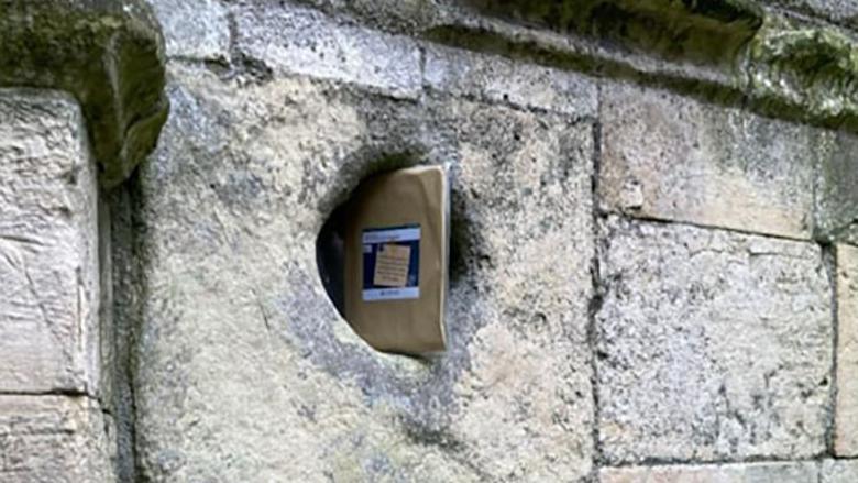 A book wrapped in an envelope hidden in a hole in a stone wall