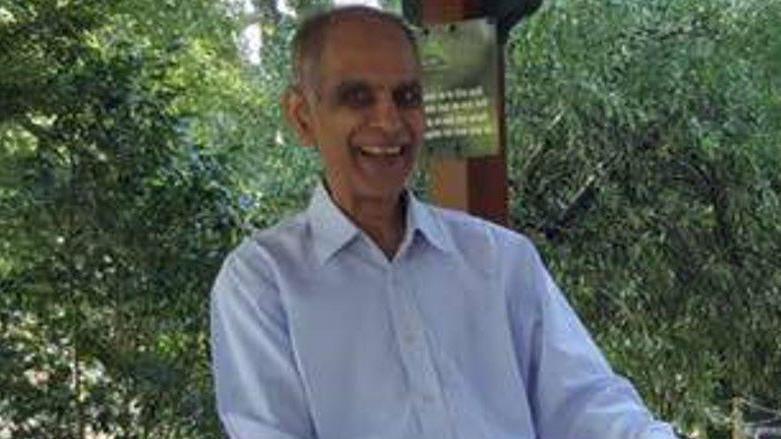 An older man in blue shirt smiling at the camera