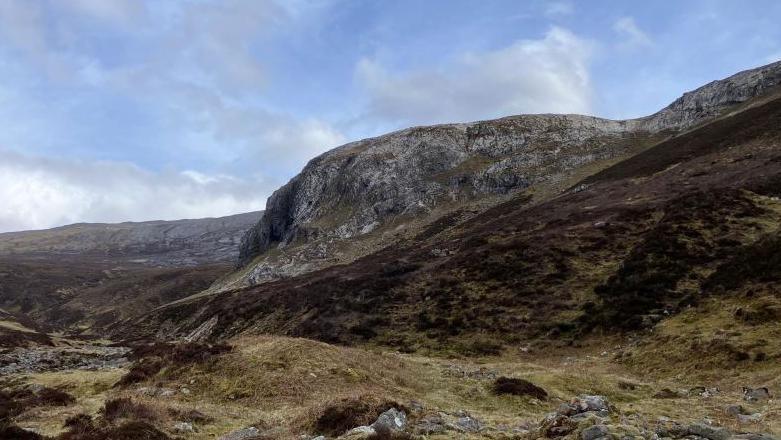 The cliffs are steep and in a vast expanse of mountain landscape.