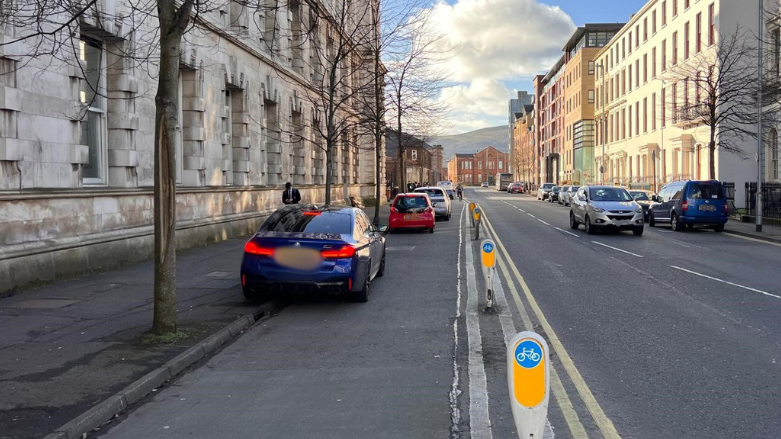 Cars parked inside a cycle lane with cycling bollard on the right