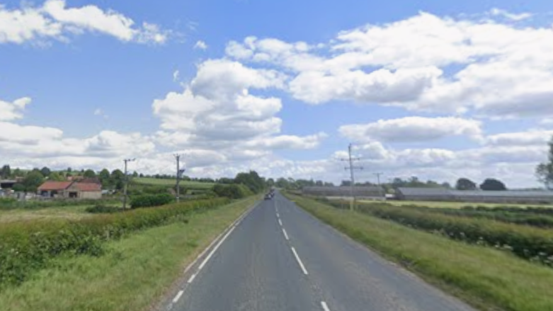 A road with fields on either side.