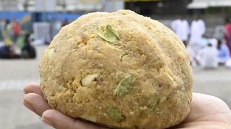 A hand holds up a famous Tirupati laddu