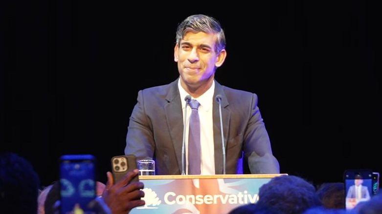 Rishi Sunak smiles at cheering crowd