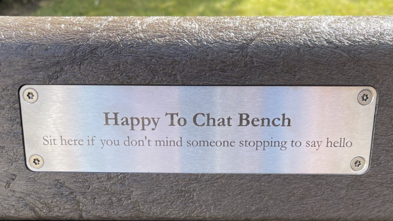 Plaque on bench which reads Happy to Chat Bench Sit here if you don't mind someone stopping to say hello 