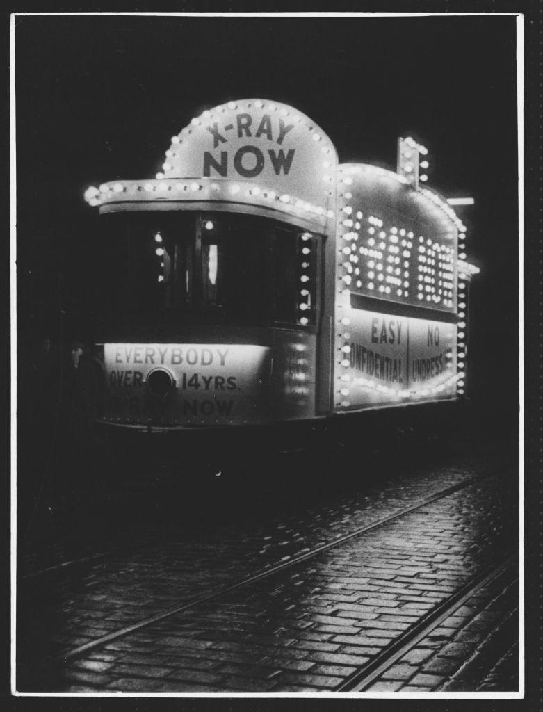 A brightly lit Glasgow tram with signs encouraging people to have an x-ray