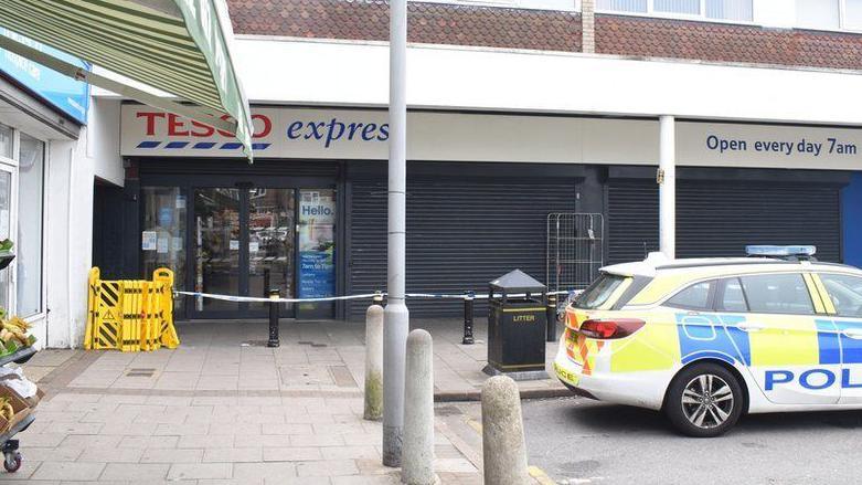 Police car and a cordon outside a Tesco Express store