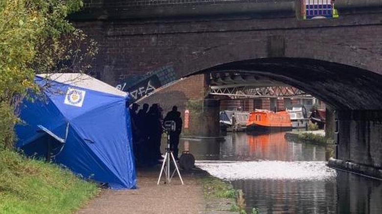 A police tent and police officers working next to a canal in Birmingham as part of the Diego Henry murder investigation