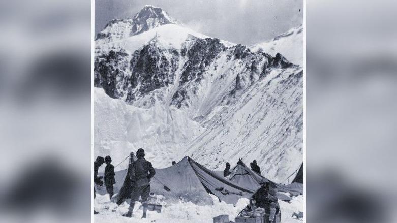 George Mallory (seated), eating breakfast by Sherpa tents at Camp 2