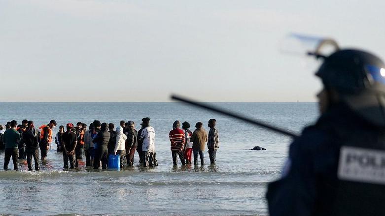 People thought to be migrants wade through the sea to board a small boat leaving the beach at Gravelines, France, in an attempt to reach the UK by crossing the English Channel.