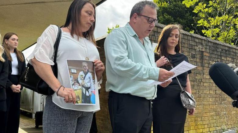 Claire Croucher (holding a photo of her daughter), John Croucher and other members of her family outside the coroner's court.